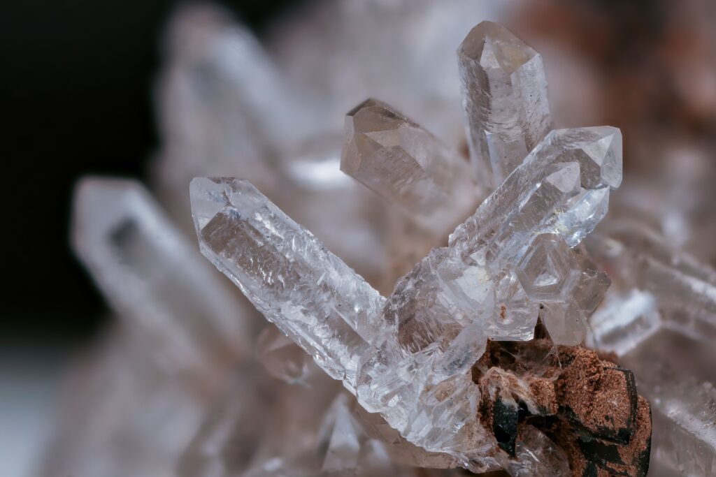 Detailed macro image of a clear quartz crystal cluster with earthy background.